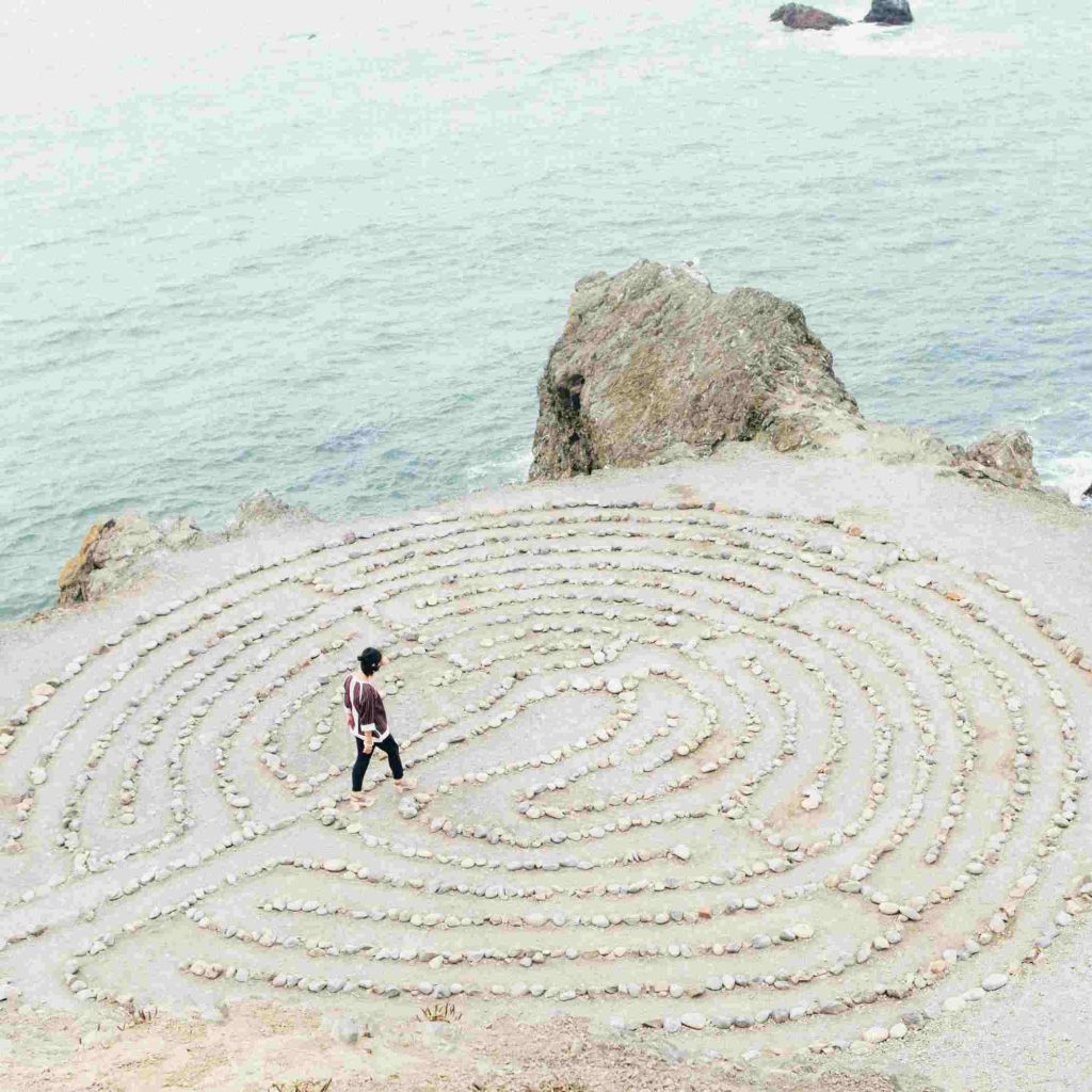 a person walking a labyrinth of life maze made out of stones on a beach