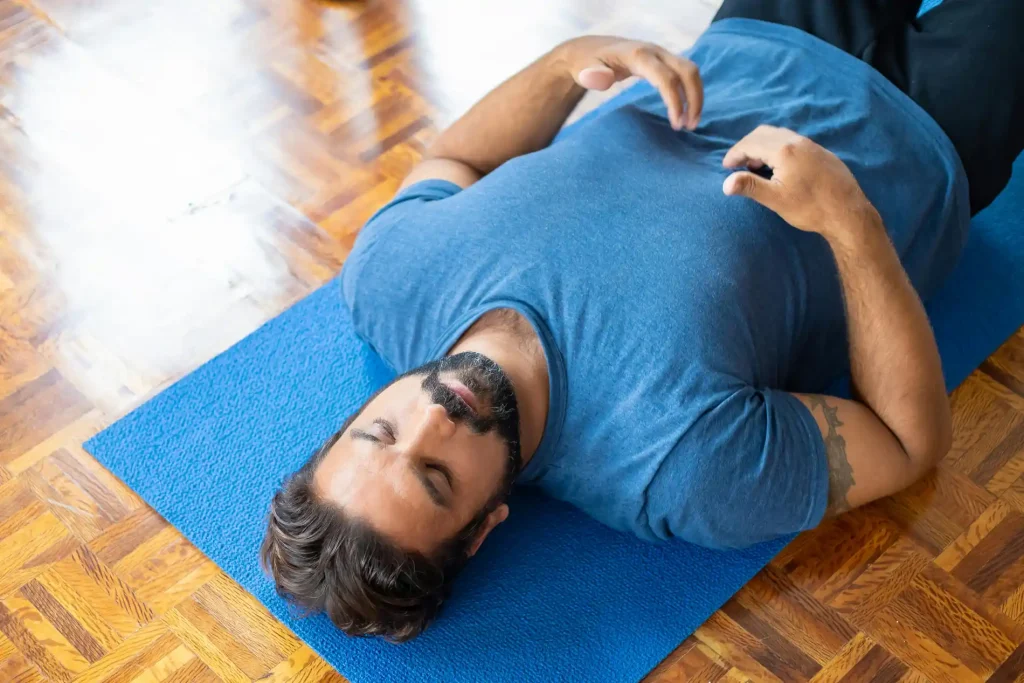 a man lying on the floor doing breathwork breathing exercises relaxed mindful