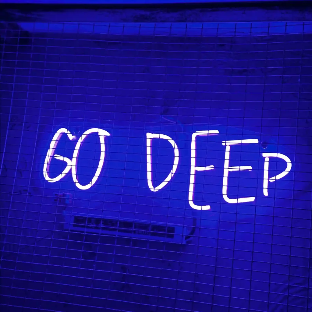 a neon sign in blue with a blue background that says Go Deep