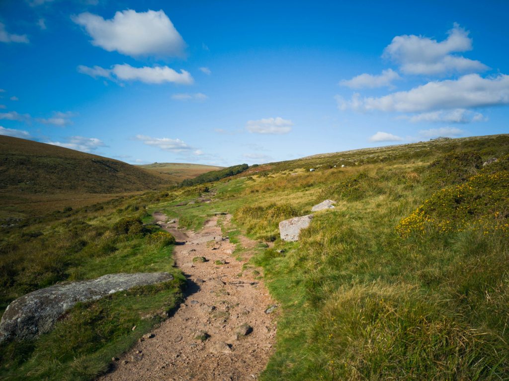 a path on dartmoor and blue skies with a little white cloud